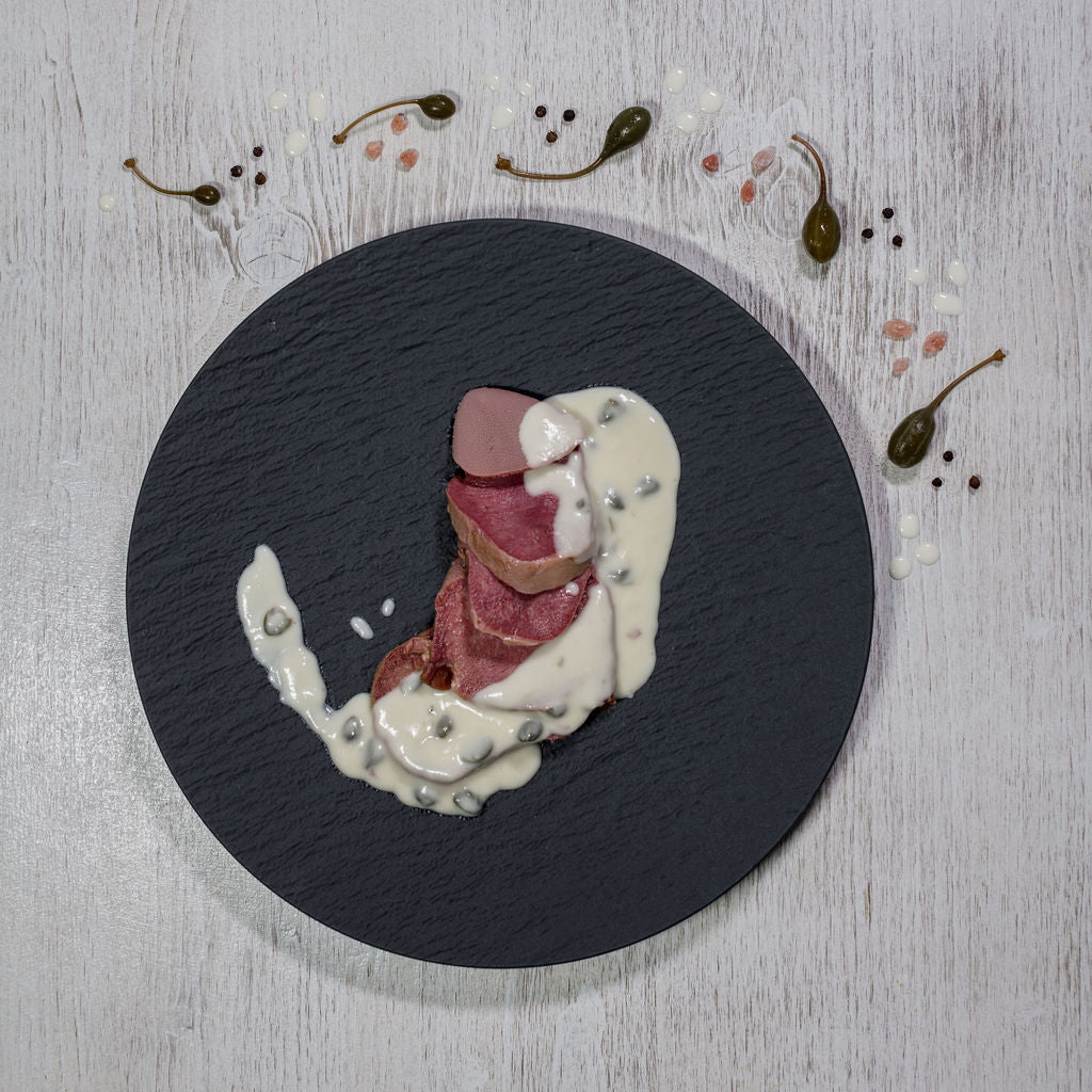 Rindszunge an Kapernsauce auf Schieferteller